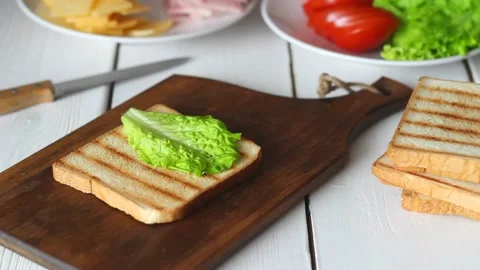 The process of making a sandwich with salad, tomato, ham and cheese. Stock Footage 147848332