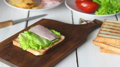 The process of making a sandwich with salad, tomato, ham and cheese. Stock Footage 147848340