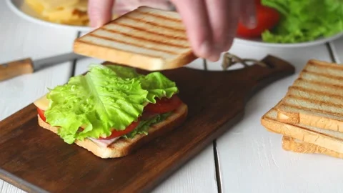 The process of making a sandwich with salad, tomato, ham and cheese. Vídeo Stock 147848367