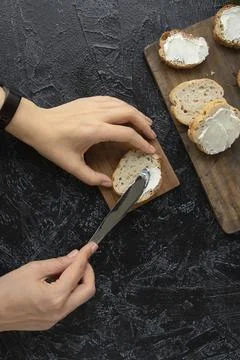 The process of making sandwiches or snacks. female hands smear cream cheese o Stock Photos