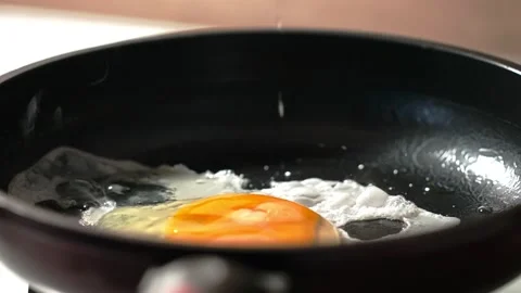 The process of making scrambled eggs from one egg in a black frying pan. Slow Stock Footage 145314601