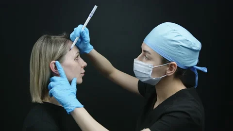 Process of making surgical marking by doctor on female face. Two shot, profile Stock Footage 239934607