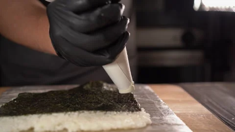 Process of making sushi, pouring cream cheese from confectioner bag Stock Footage 249392679