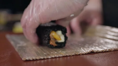 The process of making sushi rolls with dark rice. The chef's hands in gloves. Video stock 281543975