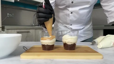 The process of making a trifle cake in transparent cups, creating confectionery Stock Footage 245537260