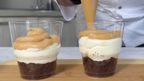 The process of making a trifle cake in transparent cups, creating confectionery Stock Footage 245537287