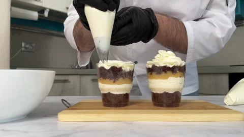 The process of making a trifle cake in transparent cups, creating confectionery Stock Footage 245537385
