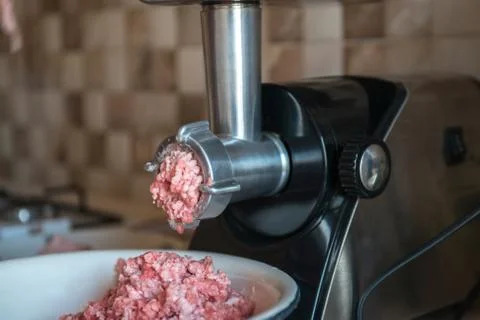 Process of meat grinding in the kitchen with mincing machine. Preparation raw Stock Photos