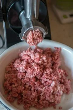 Process of meat grinding in the kitchen with mincing machine. Preparation raw Stock Photos