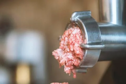 Process of meat grinding in the kitchen with mincing machine. Preparation raw Stock Photos