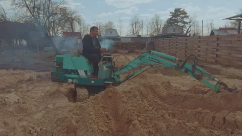 The process of the mini tractor, tractor driver, tractor uproots a tree Vídeo Stock 334058593