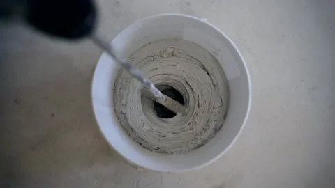 Process mixing adhesive solution in large white bucket using construction mixer Stock Footage 143699905