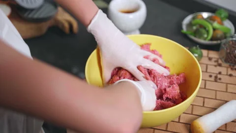 Process of mixing raw red mince with hands in yellow bowl, preparation of beef Stock Footage 225863261