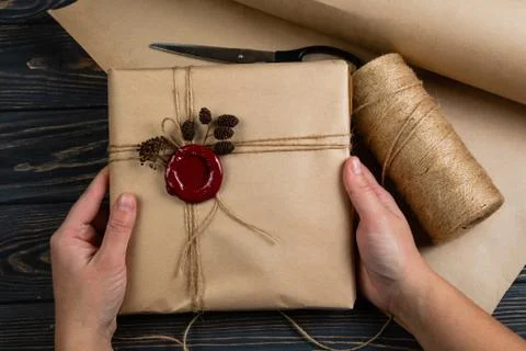 Process of package gift wrapped in craft paper, tied with string and glued wa Stock Photos