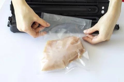 The process of packing chicken fillets in a vacuum bag using a special homemade Stock Photos