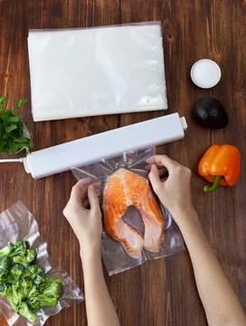 The process of packing a piece of fresh red fish into a vacuum bag and sealin Stock Photos