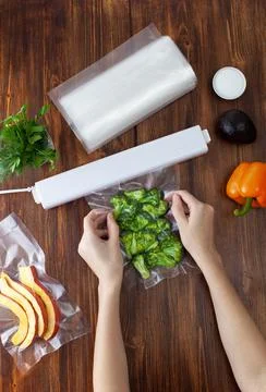 The process of packing pieces of fresh broccoli in a vacuum bag and sealing Stock Photos