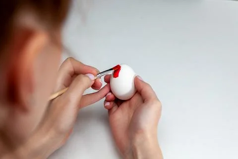 The process of painting an Easter egg with red paint. Stock Photos