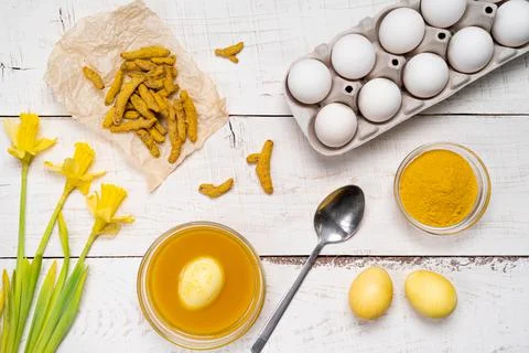 The process of painting Easter eggs with natural plant dyes, turmeric, on a w Stock Photos