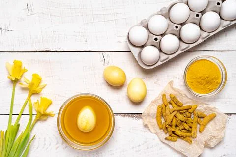 The process of painting Easter eggs with natural plant dyes, turmeric, on a w Stock Photos