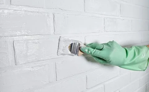 The process of painting a white brick wall with a brush and white acrylic paint Stock Photos