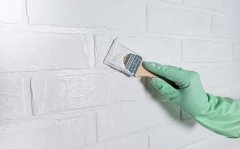 The process of painting a white brick wall with a brush and white acrylic paint Stock Photos