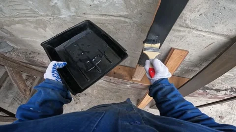 The process of painting wood. A builder paints a wooden beam black Stock-Footage 334338218