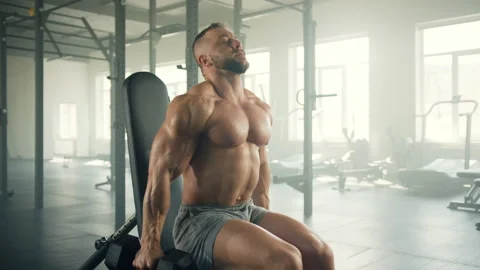 Process of performing dumbbell biceps curl by fit man in sitting position Stock Footage 240005317