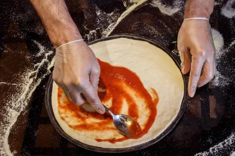 Process of pizza cooking, applying tomato sauce on it. Foto stock
