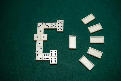 The process of playing domino on a green table. Some dominoes are connected.. Stock Photos