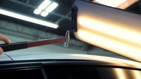 Process of pointless dent repair on car body, mechanic at the auto shop with Stock Footage 311907989