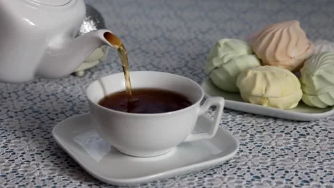 Process to pour hot tea from a kettle into a cup on a serviced Stock Footage 168433349