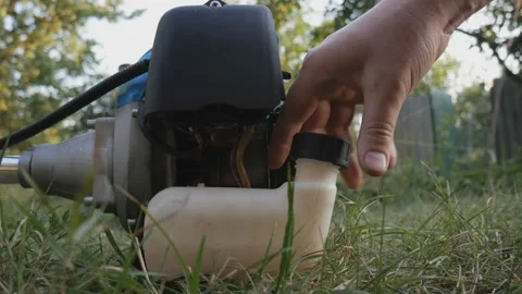 The process of pouring binzin through a watering can to start a lawn mower Stock Footage 196419890