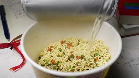 The process of pouring boiling water from a kettle into a bowl of instant noo Stock Footage 154473600