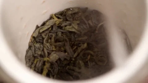 The process of pouring boiling water over the tea leaves in a white cup Stock Footage 83274084
