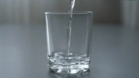 Process pouring crystal-clear water into glass, creating lively bubbles and Stock Footage 297955000