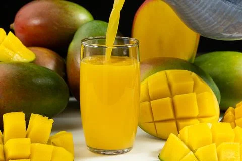 Process of pouring fresh mango juice into a glass. Stock Photos