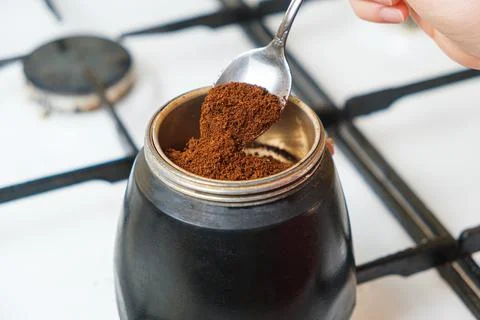 The process of pouring ground fresh coffee into a geyser coffee maker standing Stock Photos