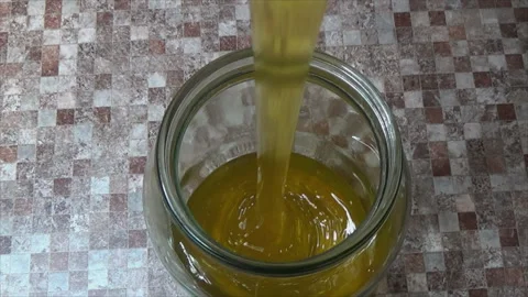 The process of pouring honey into a jar. Transfusion of yellow, sweet and Stock Footage 143691682