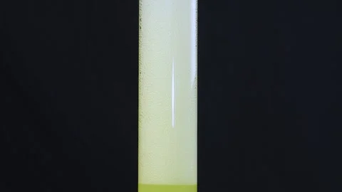 The process of pouring lemonade into a glass flask on a black background, Stock Footage 260711687