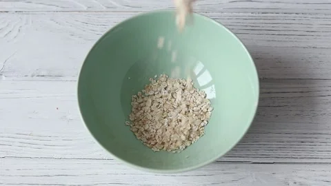 The process of pouring oatmeal into a plate, close-up top view Stock Footage 151748254