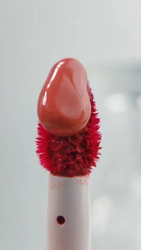Process of pouring red lip tint liquid onto the brush tip, flowing slowly. .. Stock Footage 332227428
