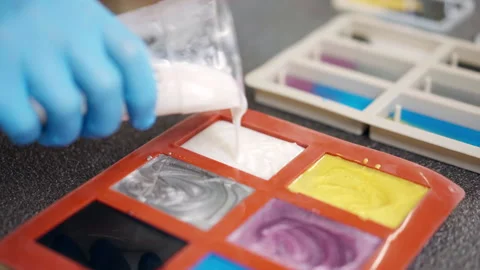 Process of pouring white colour epoxy resin from plastic cup into silicone mold Stock Footage 265892476