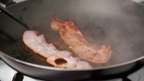 The process of preparing breakfast with bacon. Flipping bacon pieces. Stock Footage 170713243