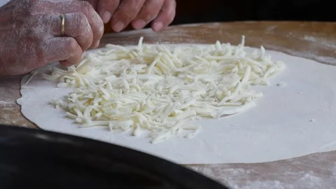 The process of preparing cheese on dough for a delightful culinary experience Stock Footage 296859564