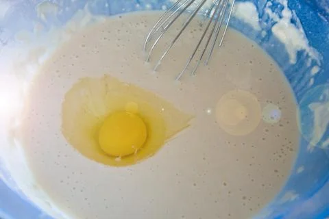 The process of preparing dough for pancakes. Cook by hand whisk metal broken  Stock Photos