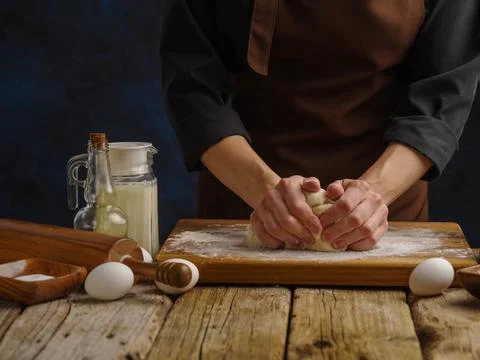 The process of preparing dough by a professional chef on a wooden cutting boa Stock Photos
