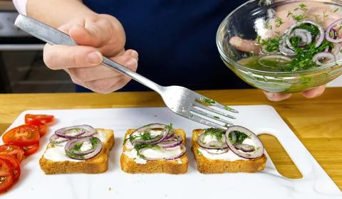 The process of preparing a festive snack on toast with sprats, onions, eggs and Stock-Fotos