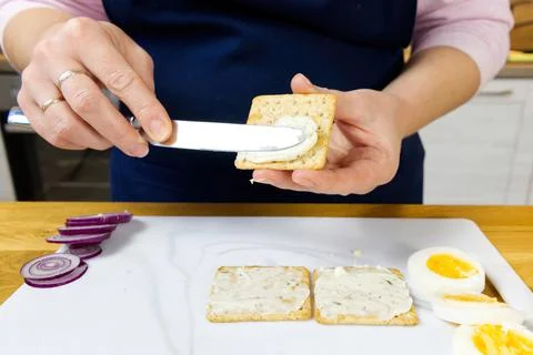 The process of preparing a festive snack on toast with sprats, onions, eggs and Stock Photos