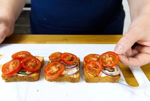 The process of preparing a festive snack on toast with sprats, onions, eggs and Stock Photos